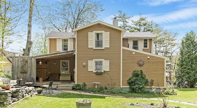 back of property featuring a chimney, a yard, and a patio