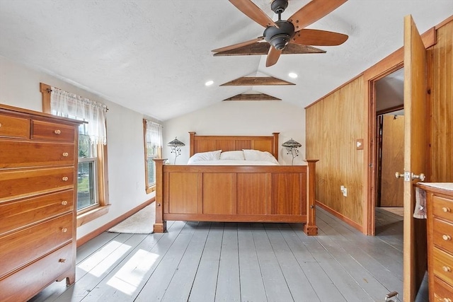 bedroom with light wood-style flooring, baseboards, lofted ceiling, and a ceiling fan