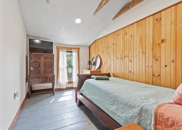 bedroom featuring wood walls, vaulted ceiling, a textured ceiling, baseboards, and hardwood / wood-style floors