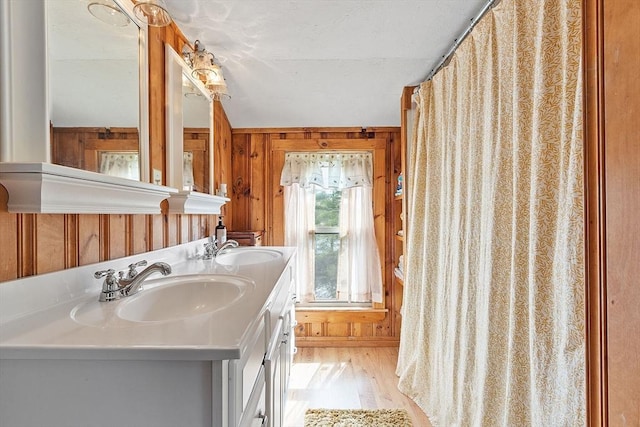 bathroom with wood walls, wood finished floors, and double vanity