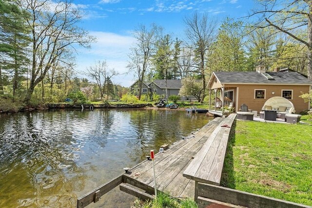 dock featuring a water view, an outdoor living space, and a yard