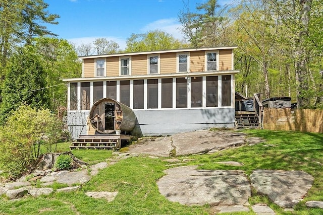 back of property featuring a sunroom and fence