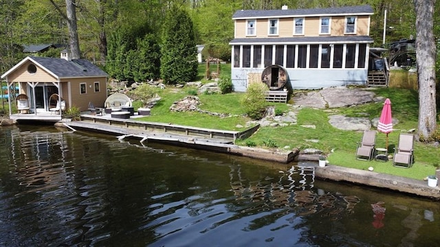 back of property with a sunroom, a water view, roof with shingles, and a forest view
