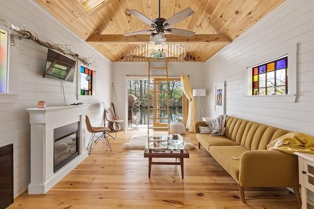 living area with wood ceiling, wooden walls, light wood-style flooring, a ceiling fan, and a glass covered fireplace