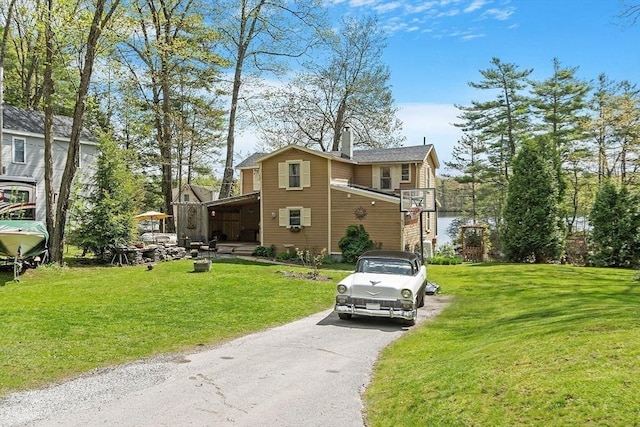 view of side of property with asphalt driveway and a lawn