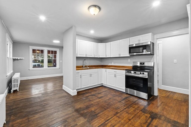 kitchen with white cabinetry, stainless steel appliances, and radiator heating unit