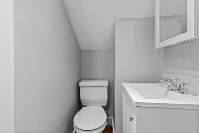 bathroom with vaulted ceiling, vanity, and toilet