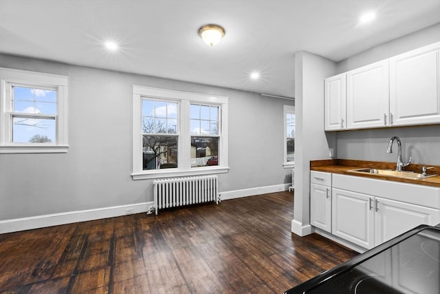 kitchen featuring white cabinetry, wood counters, radiator heating unit, and sink