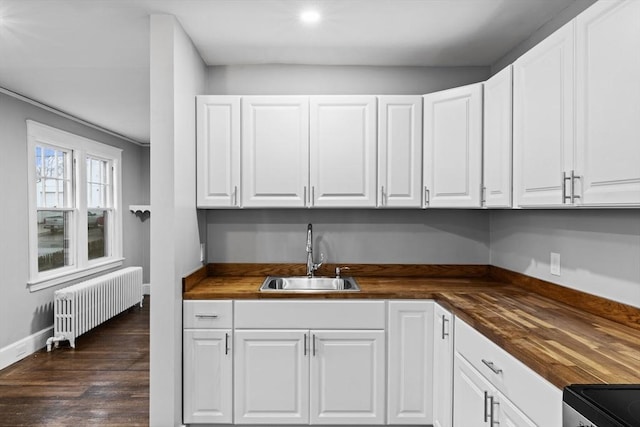 kitchen with white cabinetry, butcher block countertops, radiator heating unit, and sink