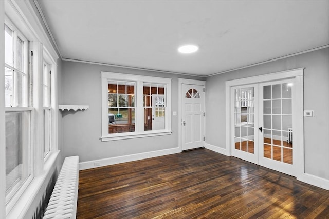 foyer entrance featuring dark hardwood / wood-style floors, ornamental molding, and french doors