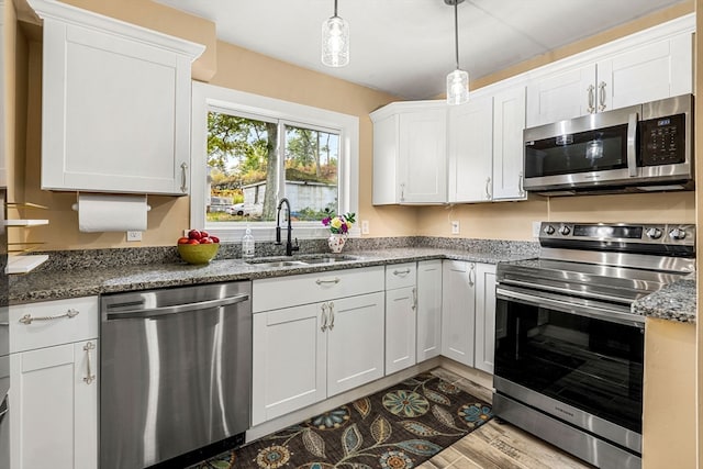 kitchen with white cabinets, light hardwood / wood-style floors, appliances with stainless steel finishes, and sink