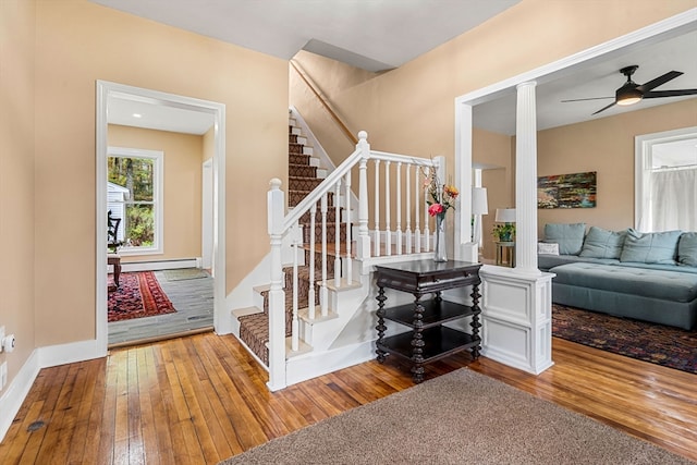 staircase featuring wood-type flooring, baseboard heating, and ceiling fan