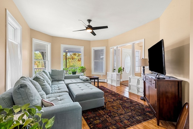 living room with a baseboard heating unit, light hardwood / wood-style flooring, and ceiling fan