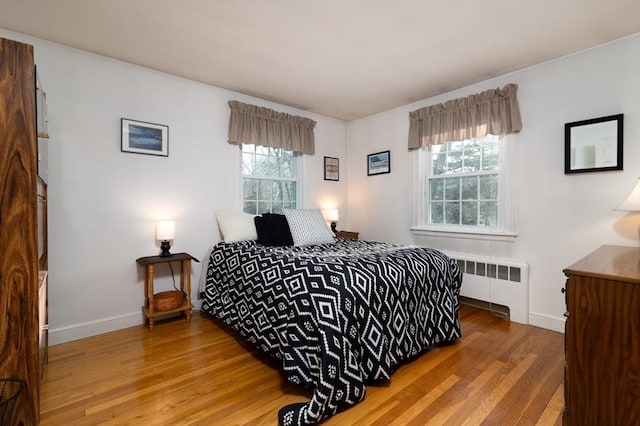 bedroom with radiator heating unit, wood finished floors, and baseboards