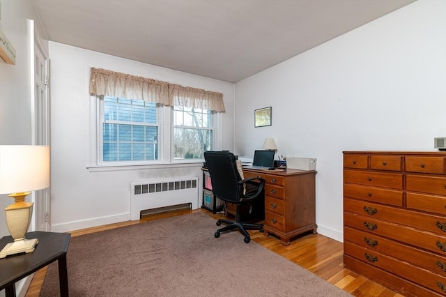 office area featuring radiator heating unit, baseboards, and light wood-style flooring