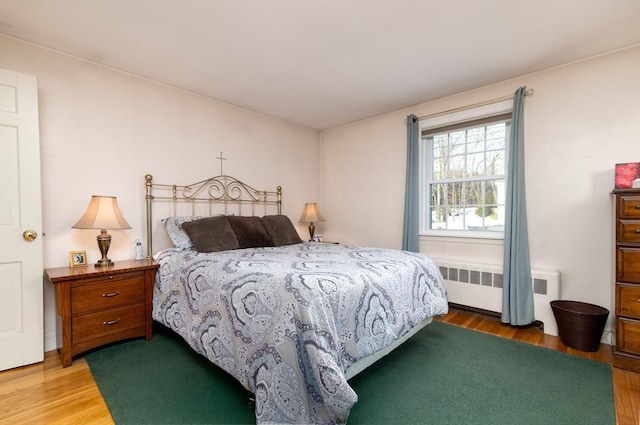 bedroom featuring radiator heating unit and wood finished floors