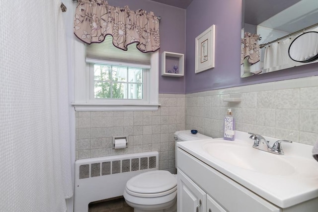 bathroom featuring toilet, radiator heating unit, shower / bathtub combination with curtain, vanity, and tile walls