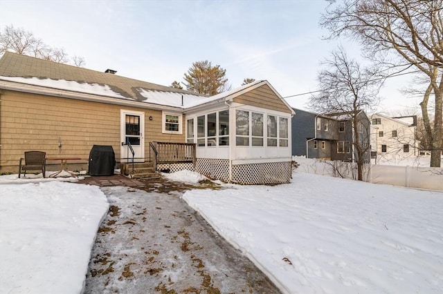 snow covered house featuring a sunroom