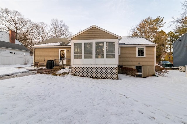 snow covered back of property featuring a garage