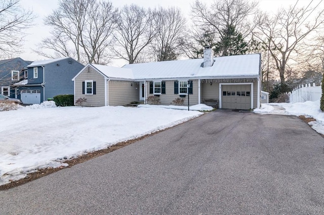 single story home with driveway, a chimney, and an attached garage