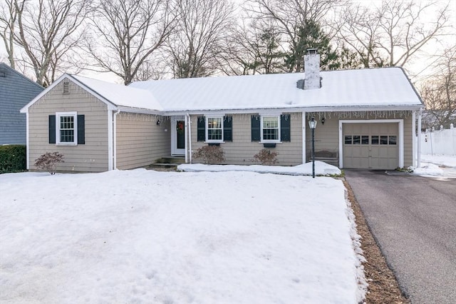 ranch-style home with aphalt driveway, a chimney, and an attached garage