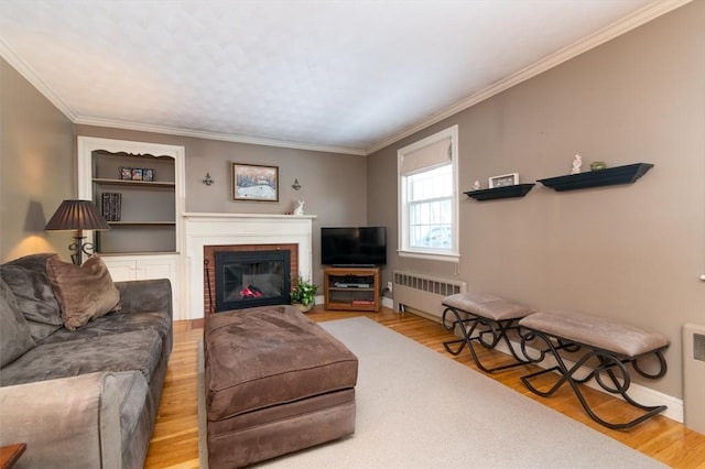 living room featuring radiator, crown molding, a fireplace, and wood finished floors