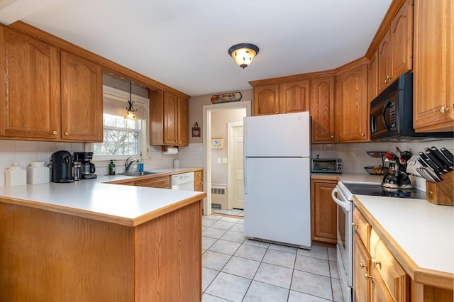 kitchen featuring light countertops, brown cabinetry, a sink, white appliances, and a peninsula