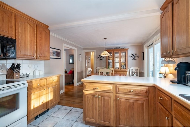 kitchen with a peninsula, white electric stove, black microwave, and light countertops