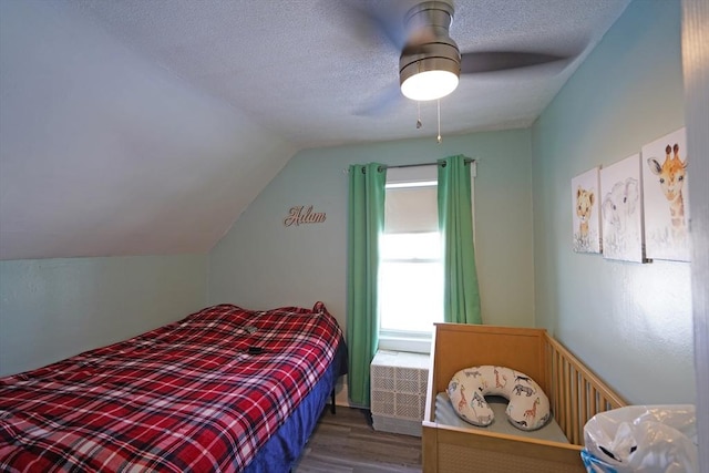 bedroom with ceiling fan, dark wood-type flooring, a textured ceiling, and vaulted ceiling