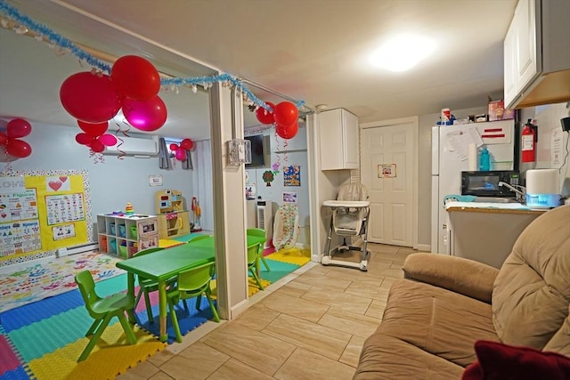 rec room with a baseboard radiator and an AC wall unit