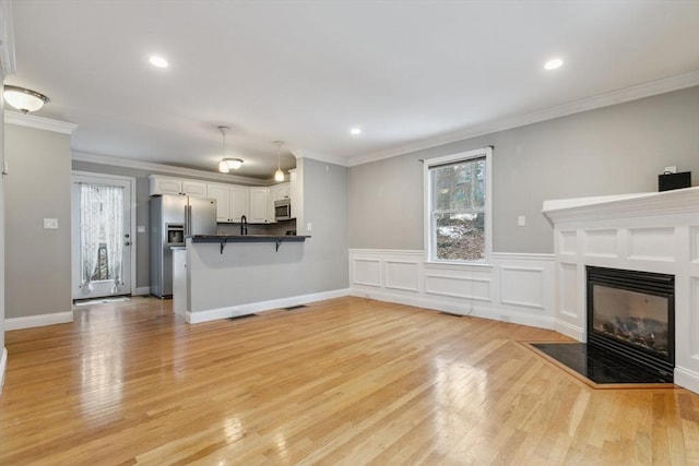 unfurnished living room featuring crown molding and light wood-type flooring