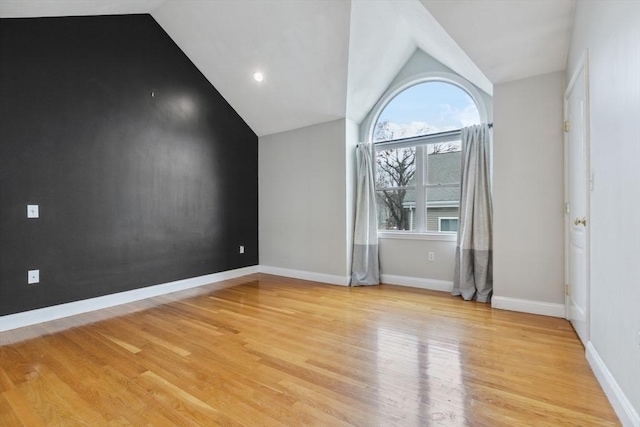 unfurnished room featuring lofted ceiling and light hardwood / wood-style flooring