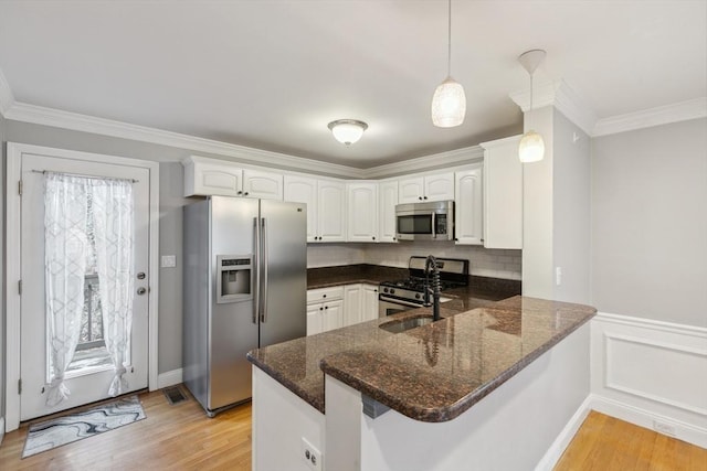 kitchen with pendant lighting, white cabinetry, kitchen peninsula, stainless steel appliances, and light hardwood / wood-style flooring