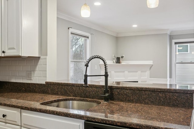 interior details featuring hanging light fixtures, sink, dark stone countertops, and white cabinets