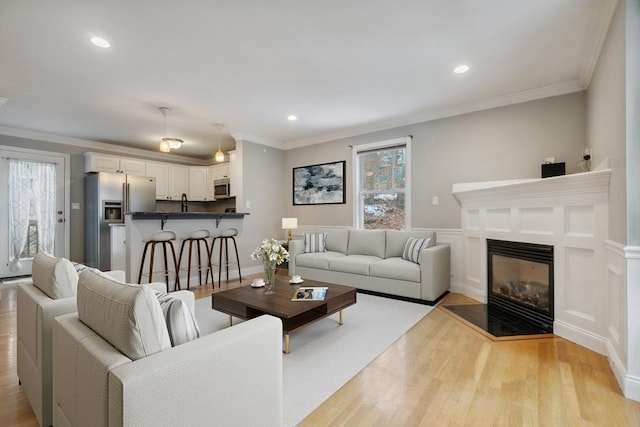 living room featuring crown molding and light hardwood / wood-style flooring