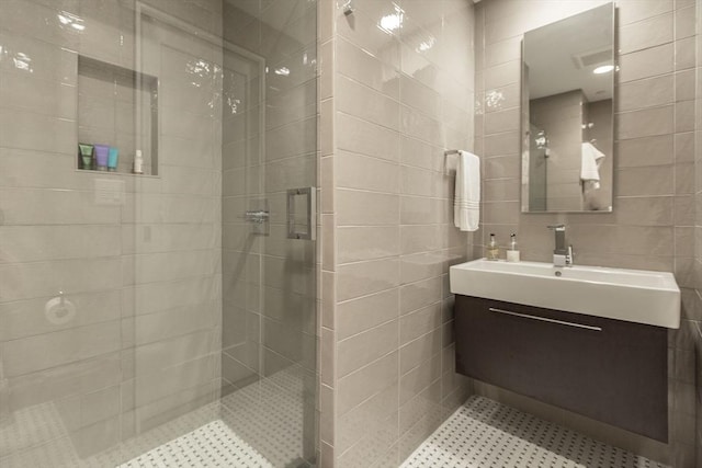 full bath with a stall shower, tile walls, and vanity