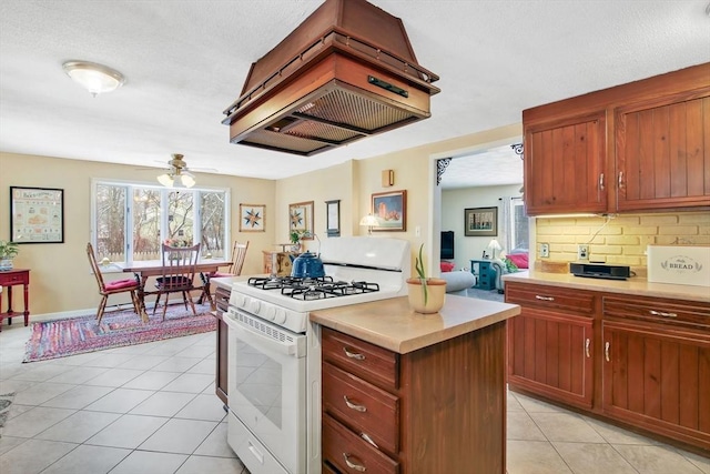 kitchen with light tile patterned flooring, a kitchen island, custom range hood, white gas range oven, and decorative backsplash