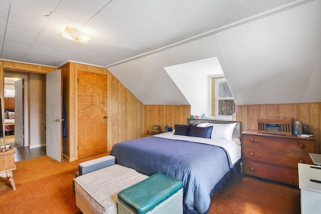 carpeted bedroom with vaulted ceiling, a closet, and wood walls