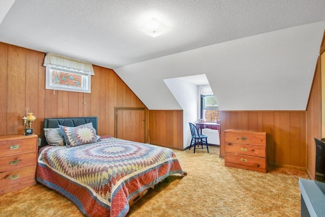 bedroom with vaulted ceiling, wooden walls, light colored carpet, and a textured ceiling