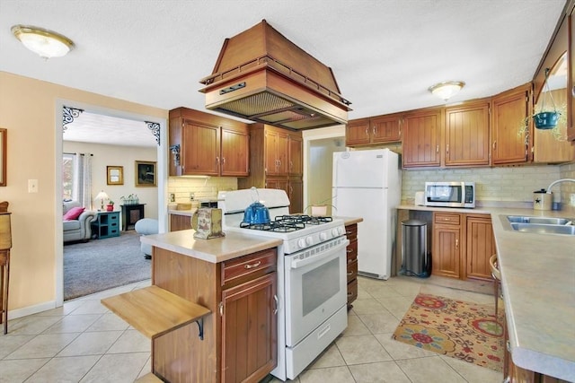 kitchen featuring island range hood, sink, light tile patterned floors, and white appliances