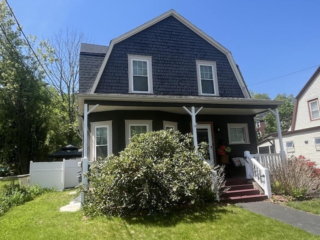dutch colonial featuring a gambrel roof, a porch, and a shingled roof