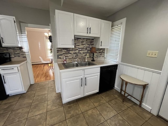 kitchen featuring black dishwasher, a sink, light countertops, a chandelier, and white cabinets