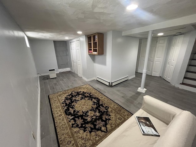 finished below grade area featuring recessed lighting, dark wood-style flooring, baseboards, and baseboard heating