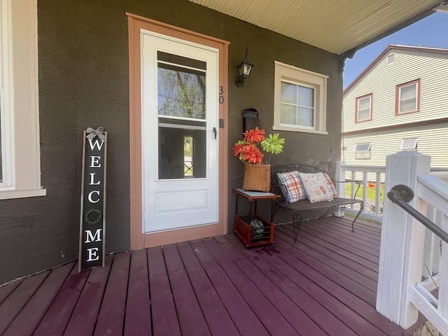 entrance to property with covered porch and stucco siding
