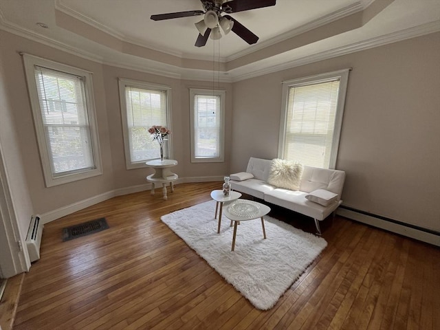 living room featuring a raised ceiling, a baseboard radiator, wood-type flooring, ornamental molding, and ceiling fan