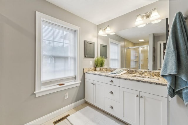 full bathroom featuring a sink, double vanity, baseboards, visible vents, and a stall shower