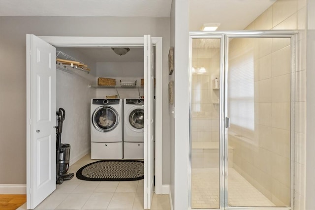 washroom with tile patterned floors, baseboards, laundry area, and washing machine and dryer