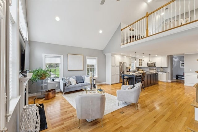 living room featuring high vaulted ceiling, ceiling fan, and light wood finished floors