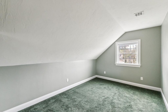 additional living space featuring carpet floors, baseboards, lofted ceiling, and visible vents