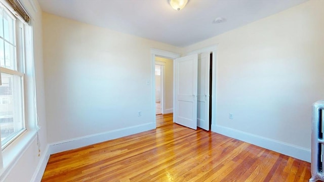 unfurnished bedroom with baseboards, multiple windows, and light wood finished floors